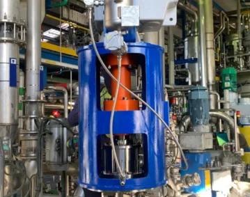 Montaje de agitador ATEX en planta química, con depósito de líquido barrera y vista del conjunto eje/acoplamiento